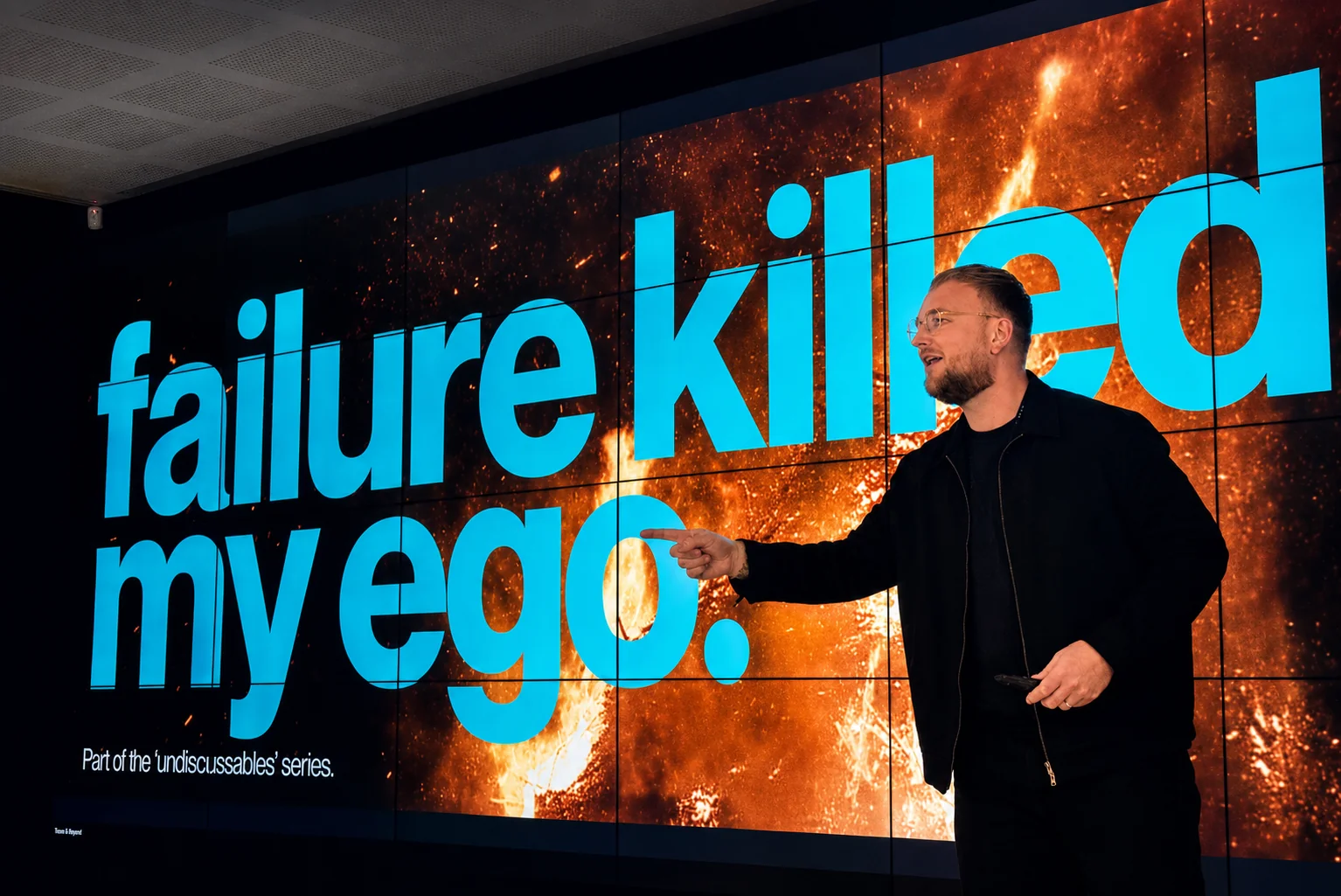 Tom Hines presenting on stage in front of a keynote screen